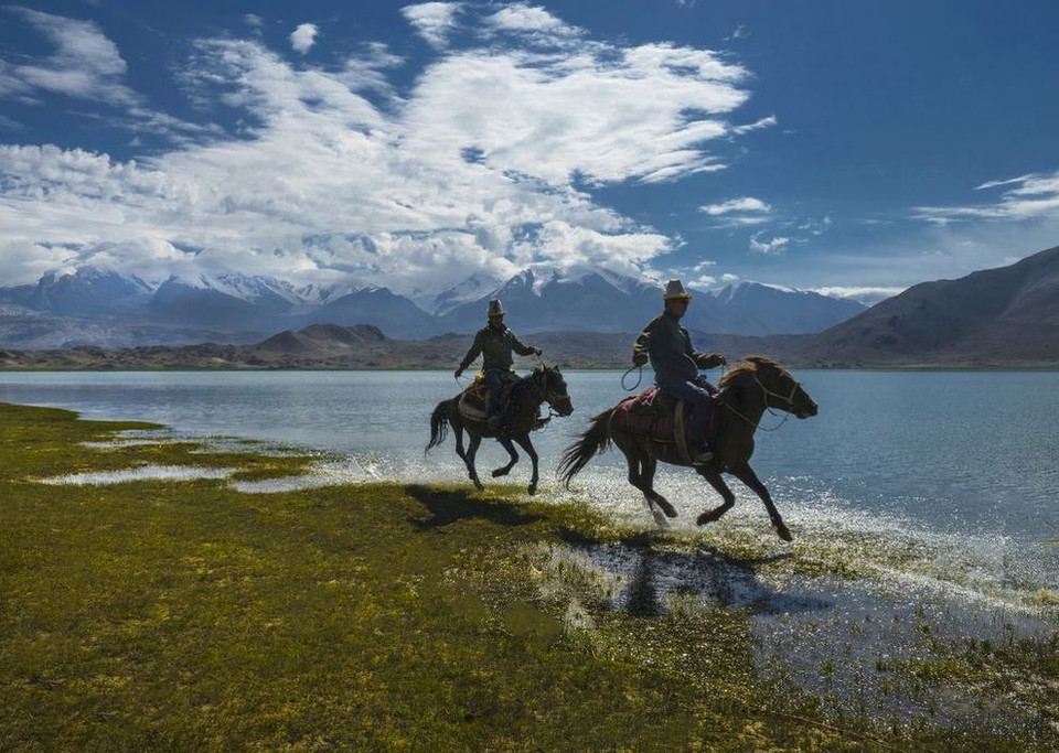 Hai người đàn ông cưỡi ngựa bên hồ Karakol ở Tân Cương, Trung Quốc. (Nguồn: NatGeo)