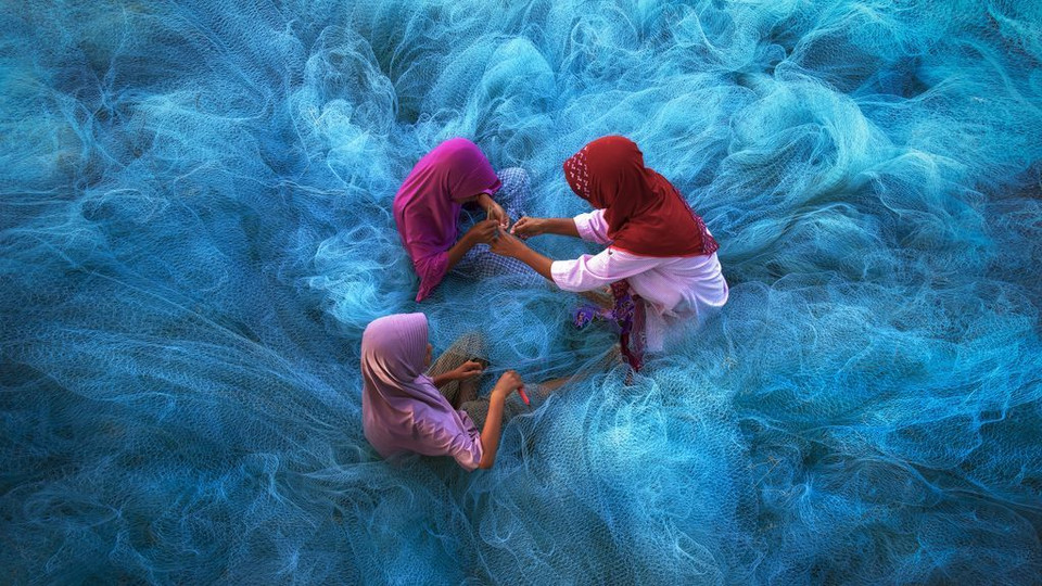 Biển lưới. (Nguồn: NatGeo) Người mẹ dạy con cách sửa lưới đánh cá ở Nakhon Si Thammarat, phía Nam Thái Lan.