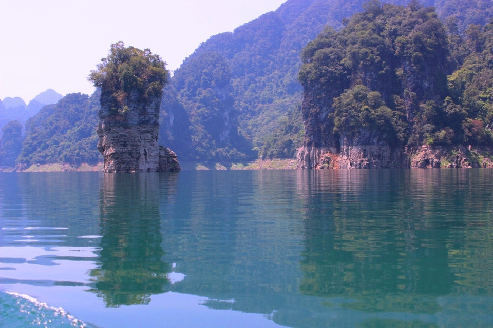 Vây lấy lòng hồ mềm mướt nũng nĩu là 99 ngọn núi thiêng sừng sững, mây vờn bốn bề, được ví như “Hạ Long cạn giữa đại ngàn.” (Ảnh: Hùng Võ-Hoàng Chiên/Vietnam+)