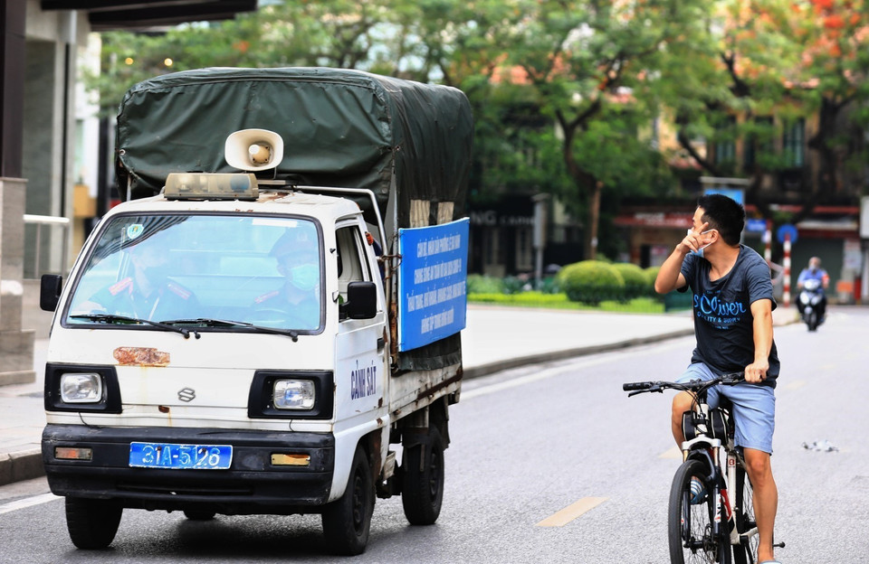 Công an phường Lê Đại Hành gọi loa nhắc nhở người dân ra đường đạp xe tập thể dục, nếu tiếp tục vi phạm sẽ tiến hành xử phạt trong những ngày thành phố thực hiện giãn cách. (Ảnh: Thành Đạt/TTXVN)