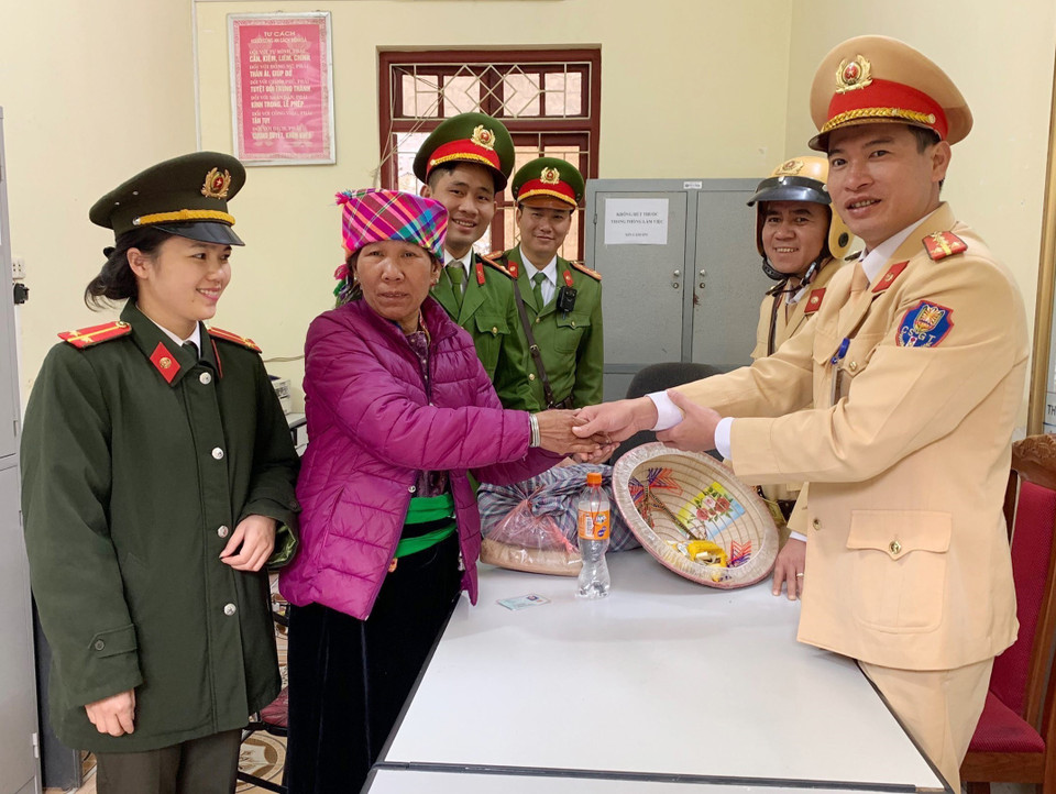 Cán bộ, chiến sỹ Công an huyện Mường La, tỉnh Sơn La hỗ trợ nhu yếu phẩm và kinh phí cho bà Đồng Thị Khân (Yên Bái) trở về nhà do bị lạc đường khi đi thăm con. (Ảnh: TTXVN phát)