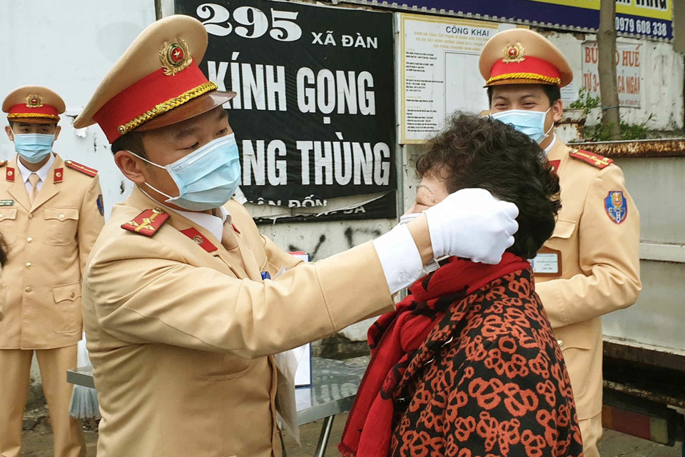 Thực hiện kế hoạch của Công an Thành phố Hà Nội trong đợt cao điểm phòng chống dịch viêm đường hô hấp cấp do chủng mới của virus Corona (nCoV) gây ra, Chi đoàn Thanh niên của Phòng Cảnh sát giao thông, Công an Thành phố Hà Nội phát động phong trào quyên góp tiền mua và phát miễn phí khẩu trang cho người tham gia giao thông, kể cả người đến xử lý vi phạm giao thông tại các đơn vị. Trong ảnh: Cảnh sát giao thông Hà Nội phát khẩu trang miễn phí cho người dân tại phố Xã Đàn. (Ảnh: Doãn Tấn/TTXVN)