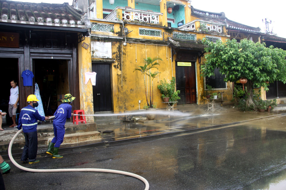Công nhân Công ty Cổ phần Công trình công cộng Hội An tiến hành vệ sinh môi trường, rửa sạch bùn đất trên các tuyến đường tại thành phố Hội An. (Ảnh: Phước Tuệ/TTXVN)