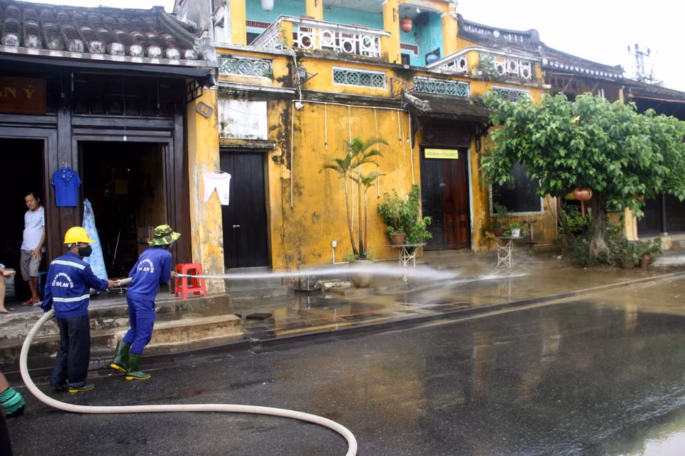 Công nhân Công ty Cổ phần Công trình công cộng Hội An tiến hành vệ sinh môi trường, rửa sạch bùn đất trên các tuyến đường tại thành phố Hội An. (Ảnh: Phước Tuệ/TTXVN)