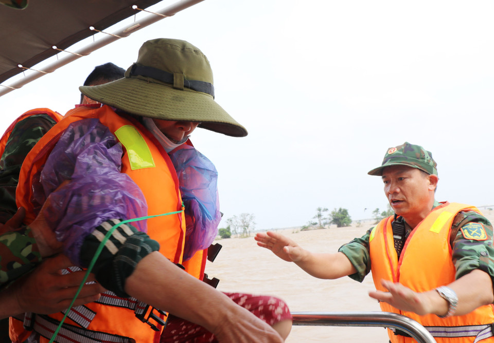Lực lượng cứu hộ đưa người dân lên xuồng an toàn. (Ảnh: Phạm Cường/TTXVN)