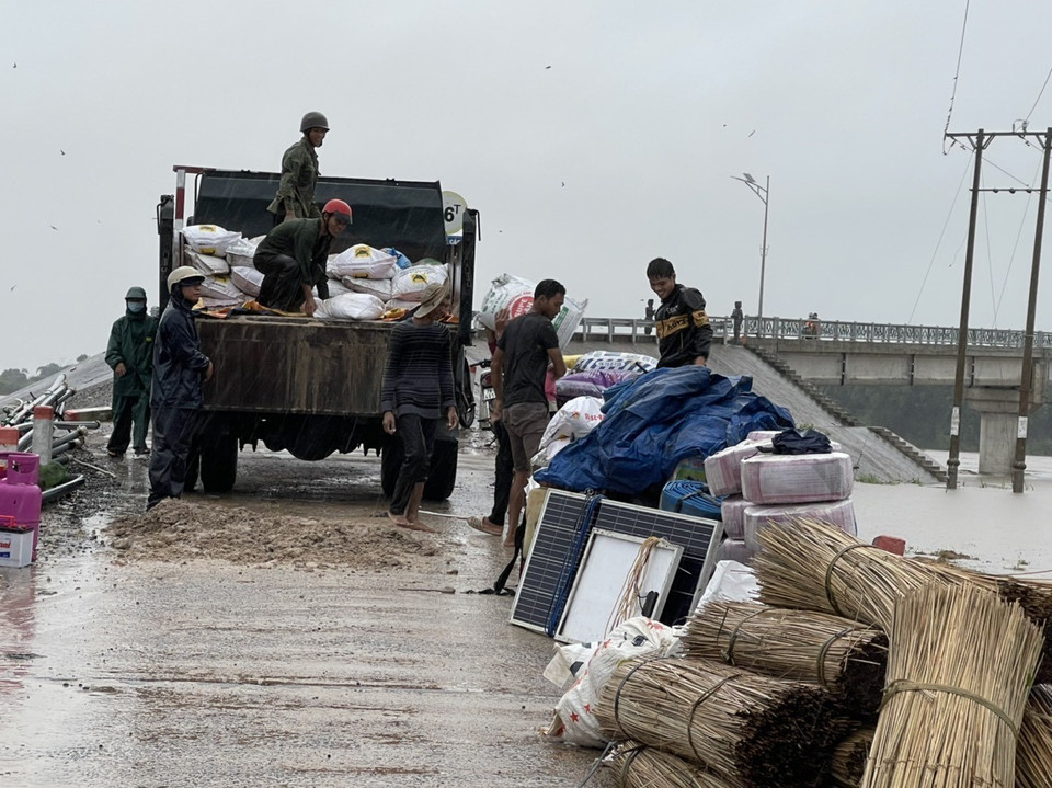 Lực lượng chức năng hỗ trợ di dời tài sản của người dân vùng lũ đến nơi an toàn. (Ảnh: Quang Thái/TTXVN)