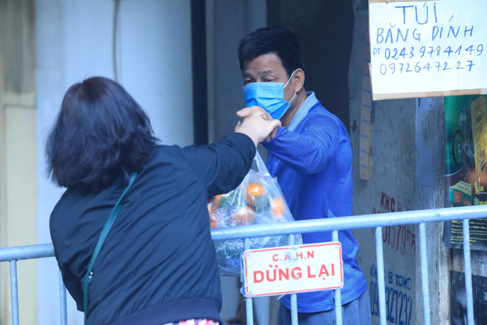 Người dân nhận đồ tiếp tế của người thân tại phường Phố Huế, quận Hai Bà Trưng. (Ảnh: Tuấn Anh/TTXVN)