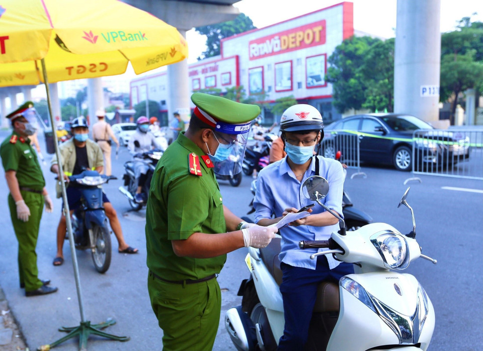 Lực lượng chức năng kiểm tra giấy tờ người đi qua chốt Cầu Diễn.(Ảnh: Hoàng Hiếu/TTXVN)
