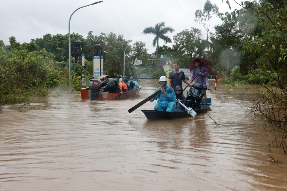 Người dân thôn Đại Lan phải di chuyển bằng thuyền do thôn bị ngập nặng. (Ảnh: Trần Việt/TTXVN)