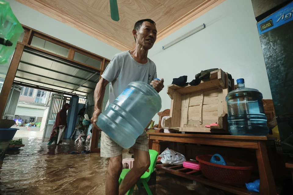 Người dân tranh thủ tích trữ đồ dùng cần thiết khi nước tràn vào nhà. (Ảnh: Minh Quyết/TTXVN)
