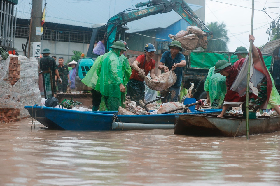 Người dân lấy đất chèn vào khu vực cửa nhà, hạn chế nước tràn vào. (Ảnh: Minh Quyết/TTXVN)