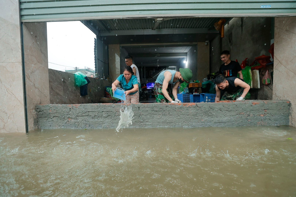 Dùng các biện pháp để hạn chế nước tràn vào nhà. (Ảnh: Minh Quyết/TTXVN)