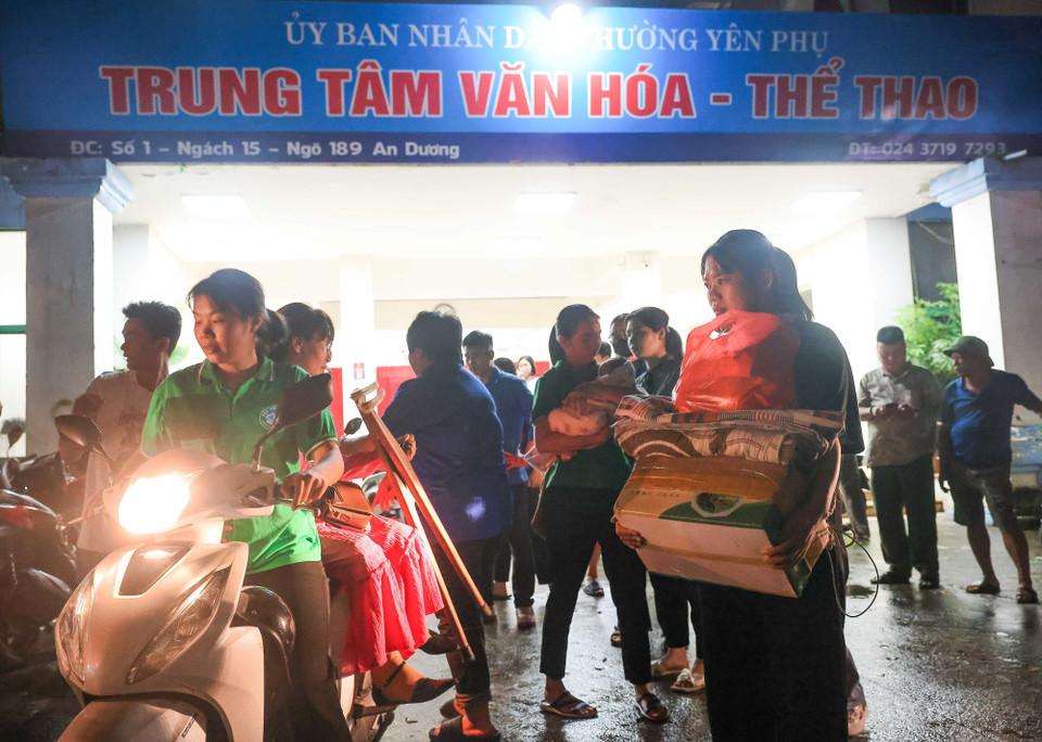 Cán bộ, nhân viên phường Yên Phụ cùng thanh niên tình nguyện hỗ trợ vận chuyển đồ đạc, đưa đón người dân về Trung tâm Văn hóa-Thể thao quận Tây Hồ. (Ảnh: Hoàng Hiếu/TTXVN)