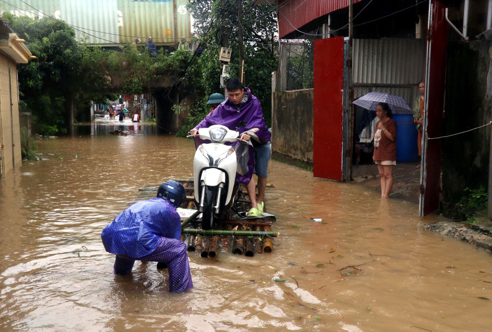 Người dân phường Lam Sơn, thành phố Hưng Yên dùng bè để đi lại khi nước sông Hồng dâng cao. (Ảnh: Đinh Văn Nhiều/TTXVN)