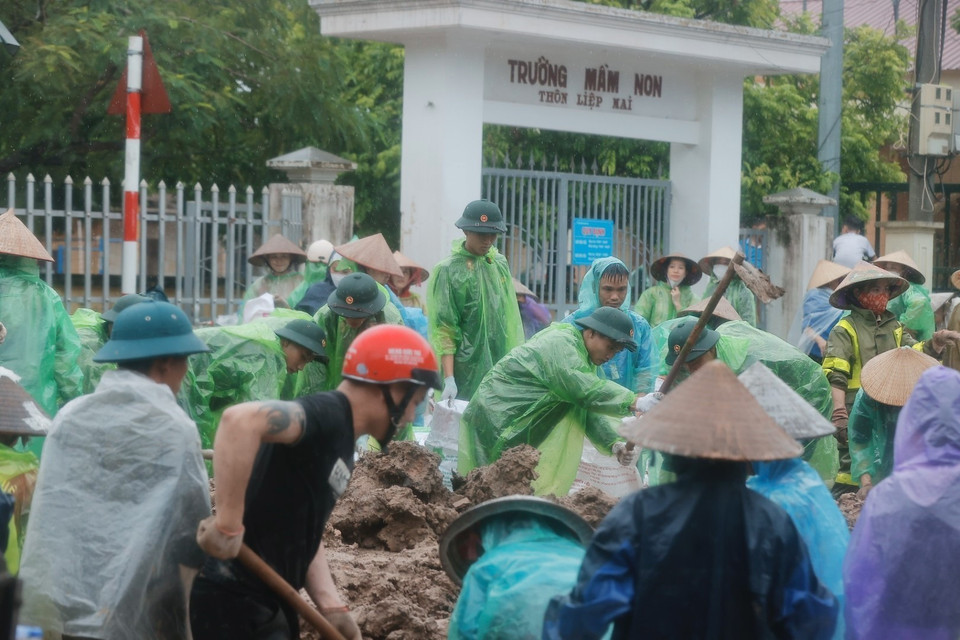 Chiến sỹ Trung đoàn 102 và người dân chuẩn bị bao tải đất để gia cố đê sông Tích, ngăn nước tràn qua đê. (Ảnh: Minh Quyết/TTXVN)