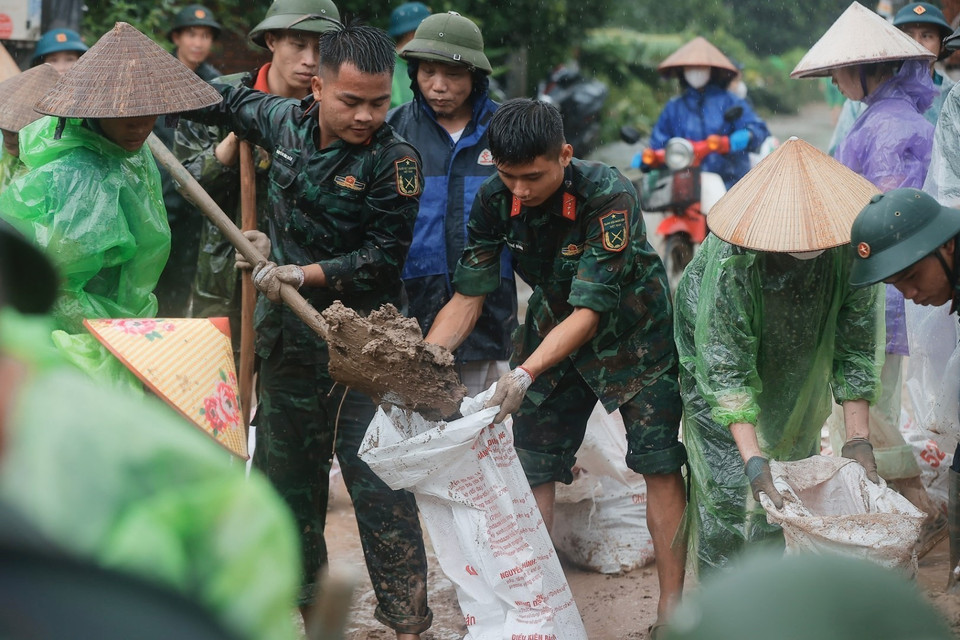 Quân đội và người dân quyết tâm ngăn không để nước tràn qua đê. (Ảnh: Minh Quyết/TTXVN)