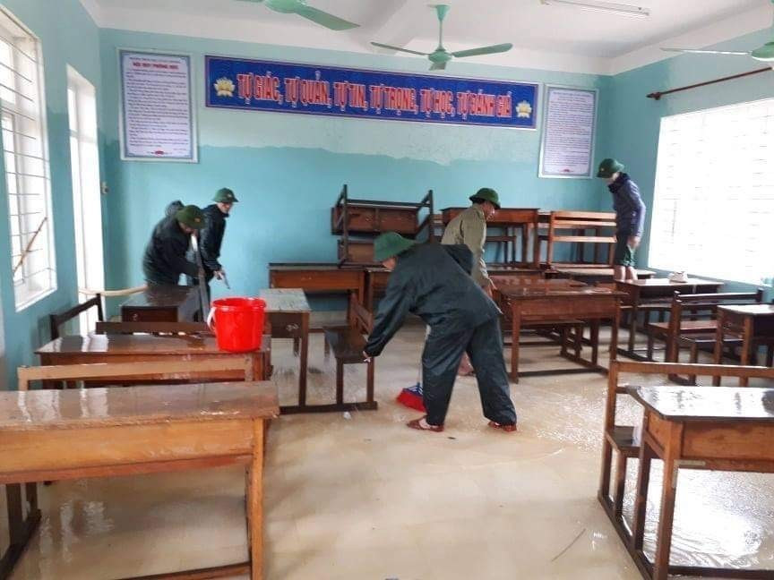 Lực lượng bộ đội cùng người dân tham gia dọn vệ sinh trường THCS Cảnh Hóa, huyện Quảng Trạch (Quảng Bình) để đón học sinh trở lại. (Ảnh: Đức Thọ/TTXVN)