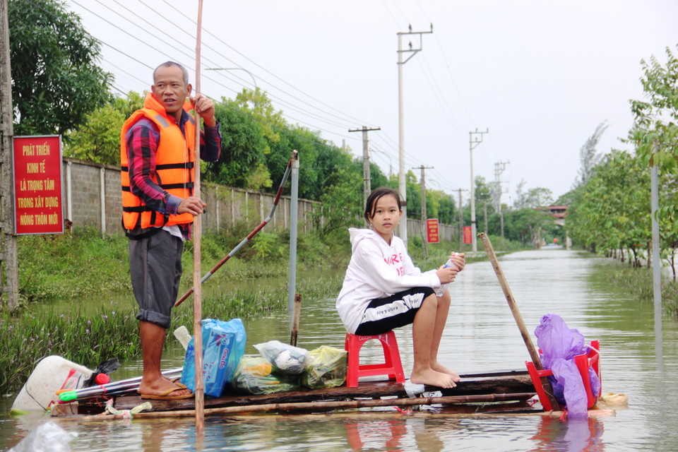 Hai cha con ở thôn Bình Tiến (xã Tân Lâm Hương, huyện Thạch Hà, Hà Tĩnh) dùng bè chuối ra để nhận hàng cứu trợ. (Ảnh: Hoàng Ngà/TTXVN)