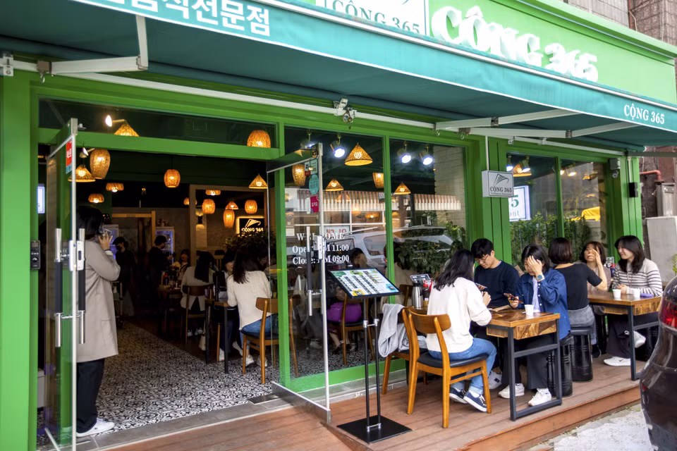 Mặc dù thời tiết bắt đầu nắng nóng song thực khách Hàn Quốc vẫn chấp nhận ngồi bên ngoài để thưởng thức món ăn truyền thống Việt Nam tại nhà hàng Cộng 365. (Ảnh: Anh Nguyên/TTXVN) 
