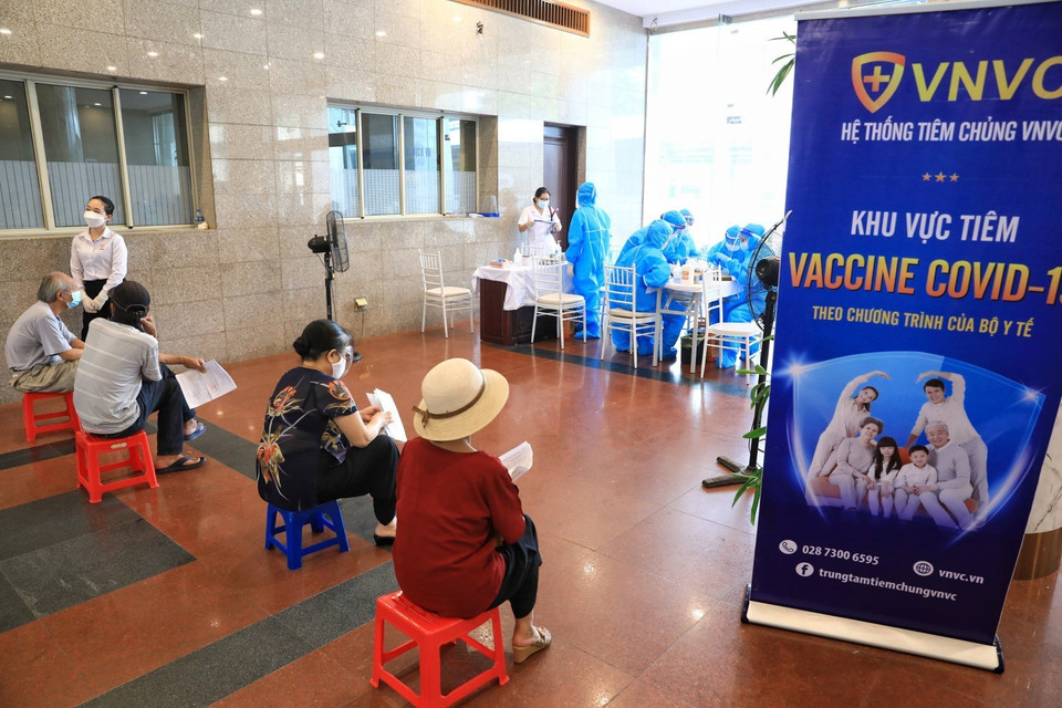 Trước khi tiêm, nhóm người cao tuổi quận Hoàn Kiếm ngồi xếp hàng đảm bảo giãn khoảng cách phòng chống dịch. (Ảnh: Thành Đạt/TTXVN)