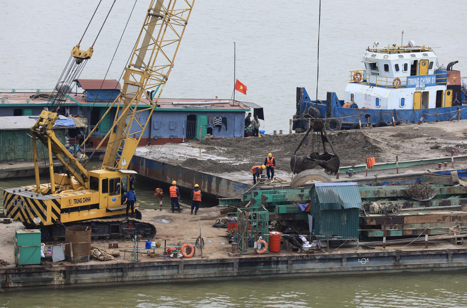 Đội ngũ công nhân cùng máy móc, phương tiện vẫn hoạt động không ngừng trên những xà lan được bố trí dọc tuyến xây dựng cầu Vĩnh Tuy 2. (Ảnh: Hoàng Hiếu/TTXVN)