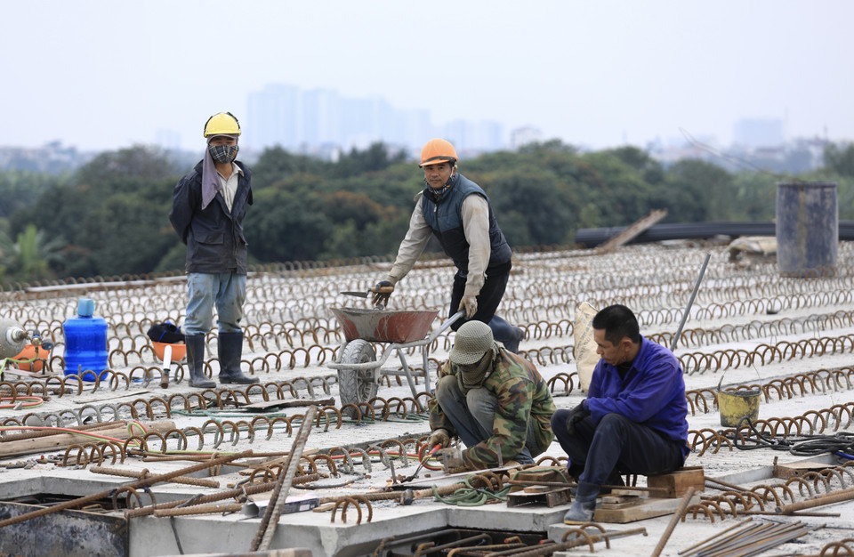 Các công nhân vẫn tiếp tục thi công và đón Tết Dương lịch 2022 ngay trên công trường Cầu Vĩnh Tuy 2. (Ảnh: Hoàng Hiếu/TTXVN)