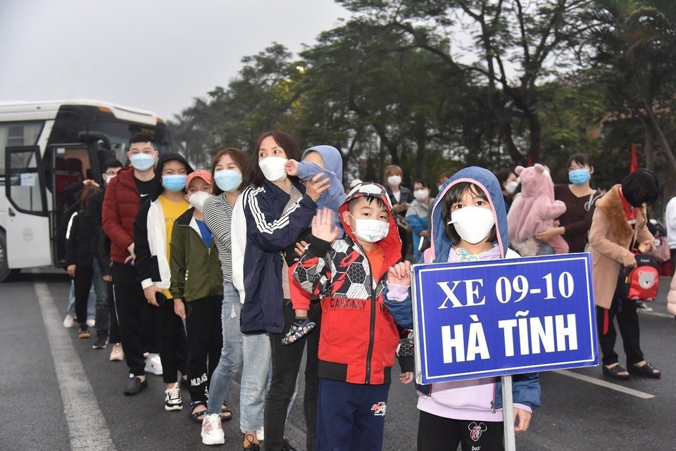 Gia đình công nhân lao động xếp hàng lên xe. (Ảnh: TTXVN phát)