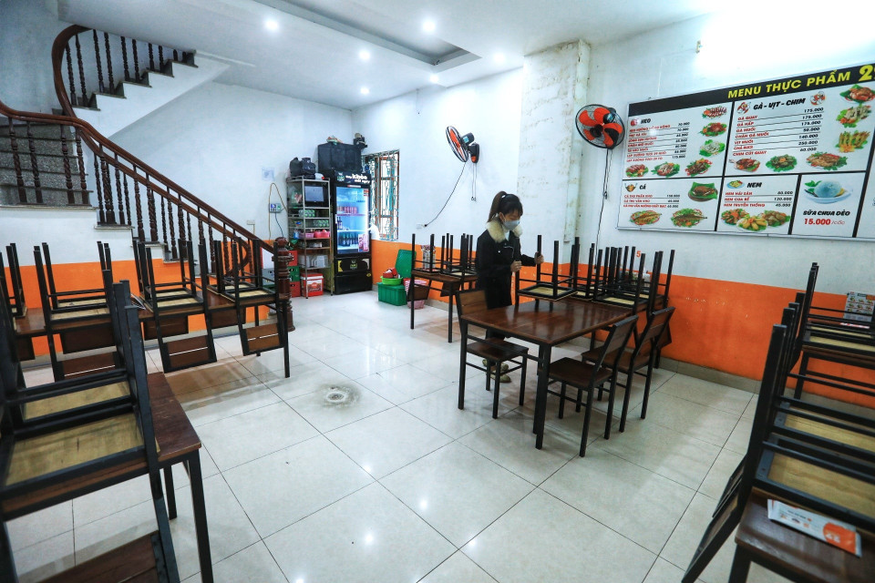 Nhân viên một cửa hàng trên phố Đội Cấn, quận Ba Đình dọn dẹp cửa hàng, không phục vụ khách ăn tại chỗ sau 12 giờ ngày 27/12/2021. (Ảnh: Tuấn Anh/TTXVN)