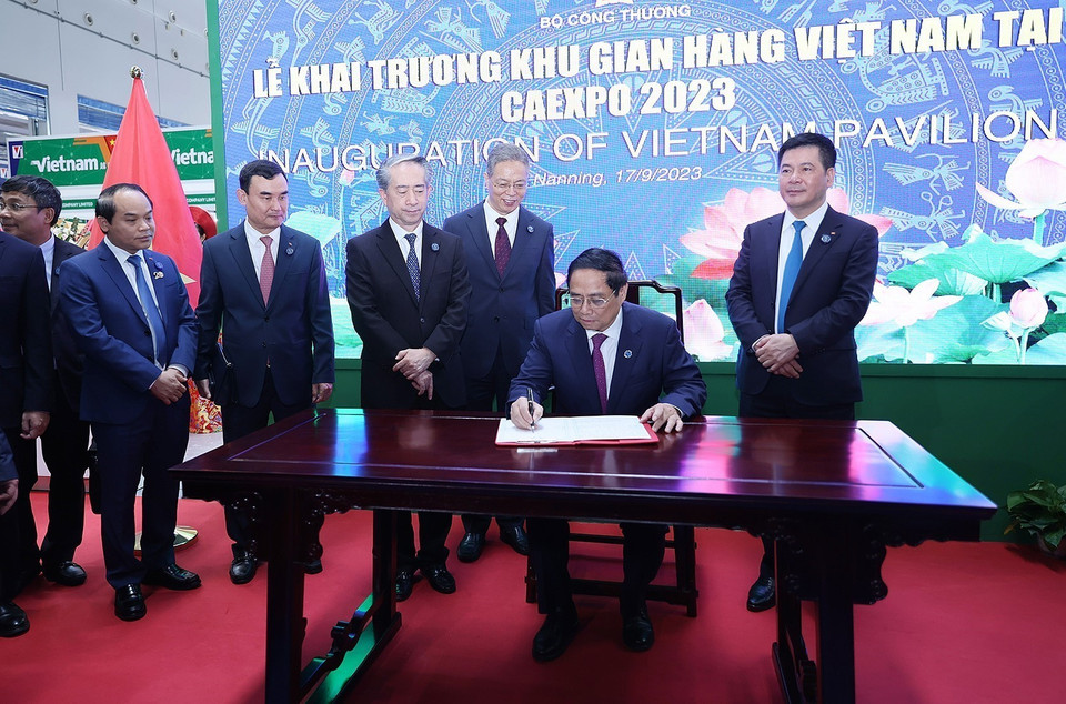 Thủ tướng Phạm Minh Chính ký lưu niệm khi đến khai trương khu gian hàng thương mại Việt Nam. (Ảnh: Dương Giang/TTXVN)