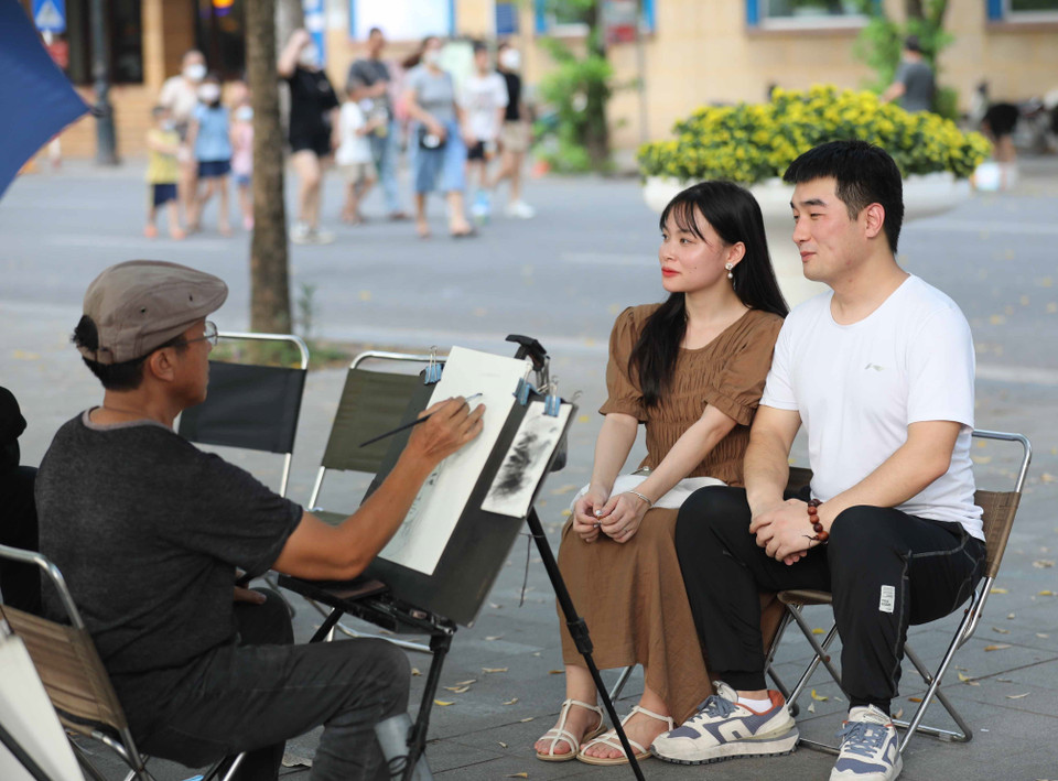 Du khách trải nghiệm vẽ truyền thần trong không gian đi bộ hồ Hoàn Kiếm. (Ảnh: Thanh Tùng/TTXVN)