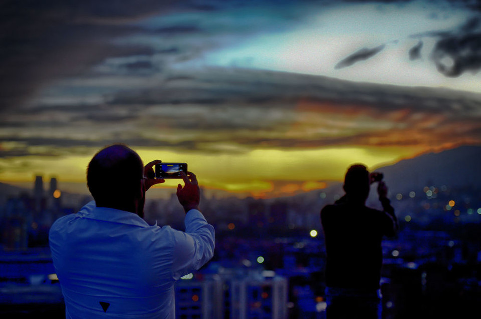 Những người đàn ông chụp cảnh hoàng hôn tại Caracas, Venezuela, ngày 3/5. (Nguồn: sputniknews.com)