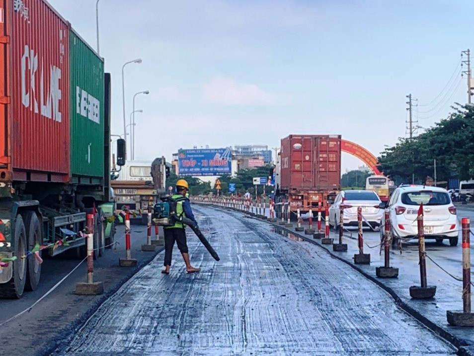 Công nhân thổi bụi để thi công thảm bêtông nhựa nhằm đảm bảo độ dính bám. (Ảnh: Việt Hùng/Vietnam+)