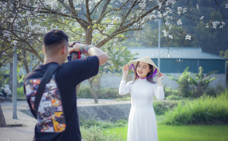 Nhiều bạn trẻ thích thú lưu giữ lại những khoảnh khắc với hoa ban. (Ảnh: Xuân Tư/TTXVN)