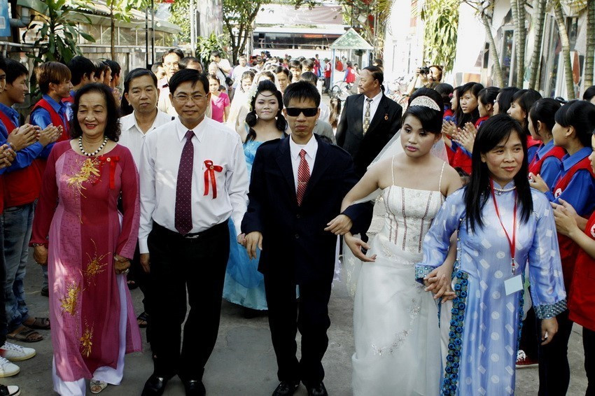 Lãnh đạo Trung tâm Nhân đạo Quê Hương (Bình Dương) cùng các cặp vợ chồng khuyết tật tại Lễ cưới tập thể cho 12 cặp vợ chồng là nạn nhân chất độc da cam/dioxin, khiếm thị và khuyết tật vận động, hiện đang sinh sống và làm việc tại Trung tâm (2012). (Ảnh: Thế Anh/TTXVN)