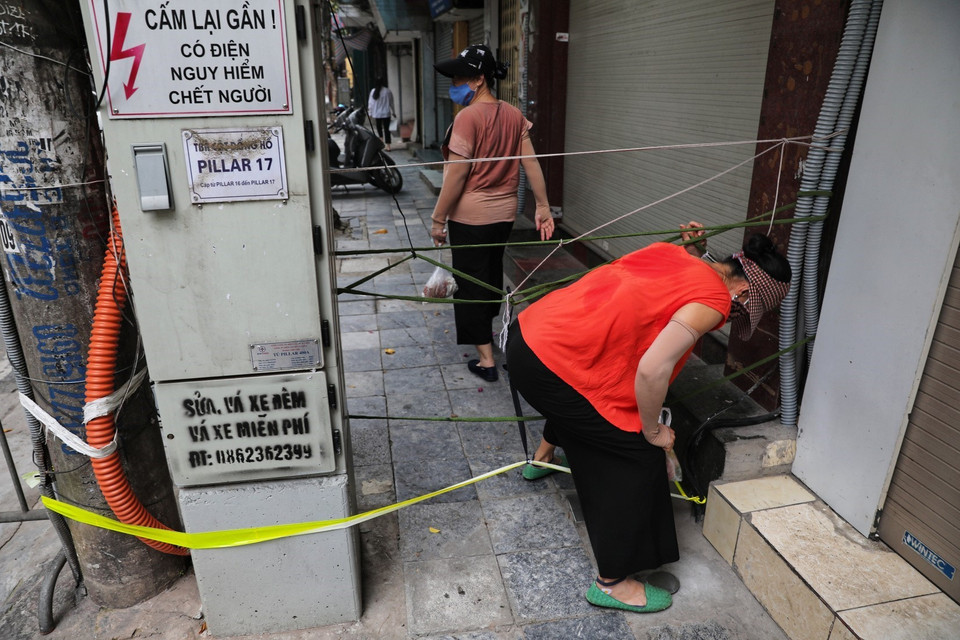 Một số bà nội trợ do ngại đi vòng xa đã chui qua "chốt cứng" trên phố Mã Mây để về nhà. (Ảnh: Thành Đạt/TTXVN)