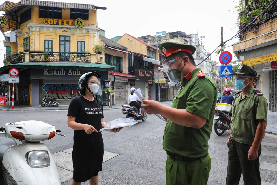 Công an phường Hàng Buồm kiểm tra chặt chẽ giấy xác nhận đi đường theo quy định mới. (Ảnh: Thành Đạt/TTXVN)