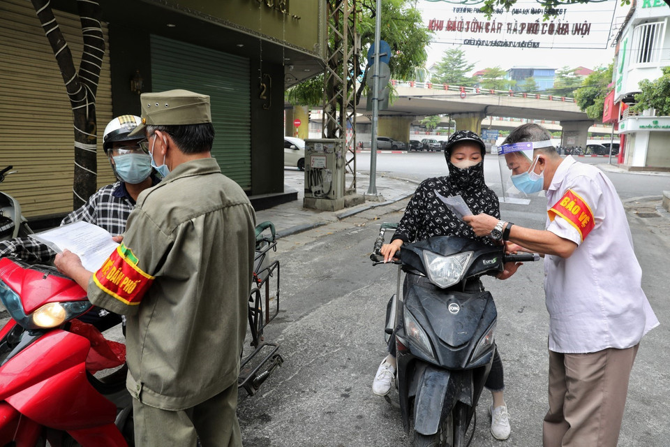 Thành viên Tổ phòng, chống COVID cộng đồng phường Hàng Buồm kiểm tra, nhắc nhở người dân hoàn thiện các mục còn thiếu đối với giấy đi đường theo quy định mới. (Ảnh: Thành Đạt/TTXVN)