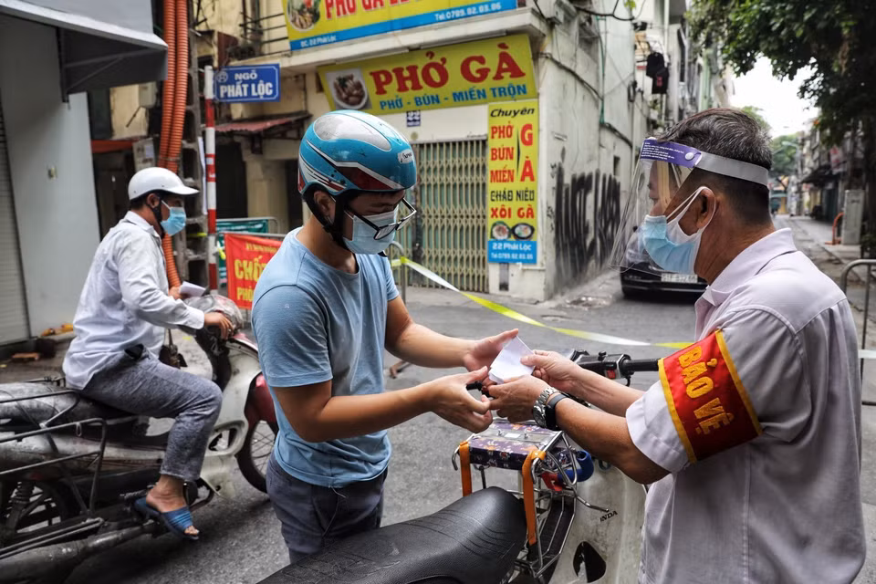 Thành viên Tổ phòng, chống COVID cộng đồng phường Hàng Buồm kiểm tra giấy đi đường theo quy định mới của người dân khi ra vào địa bàn. (Ảnh: Thành Đạt/TTXVN)
