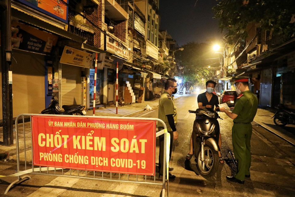 Lực lượng chức năng phường Hàng Buồm kiểm tra giấy đi đường của người dân khi ra khỏi địa bàn (Ảnh chụp lúc 23 giờ ngày 9/8). (Ảnh: Thành Đạt/TTXVN)