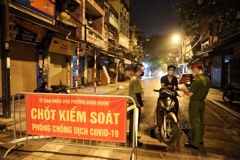 Lực lượng chức năng phường Hàng Buồm kiểm tra giấy đi đường của người dân khi ra khỏi địa bàn (Ảnh chụp lúc 23 giờ ngày 9/8). (Ảnh: Thành Đạt/TTXVN)