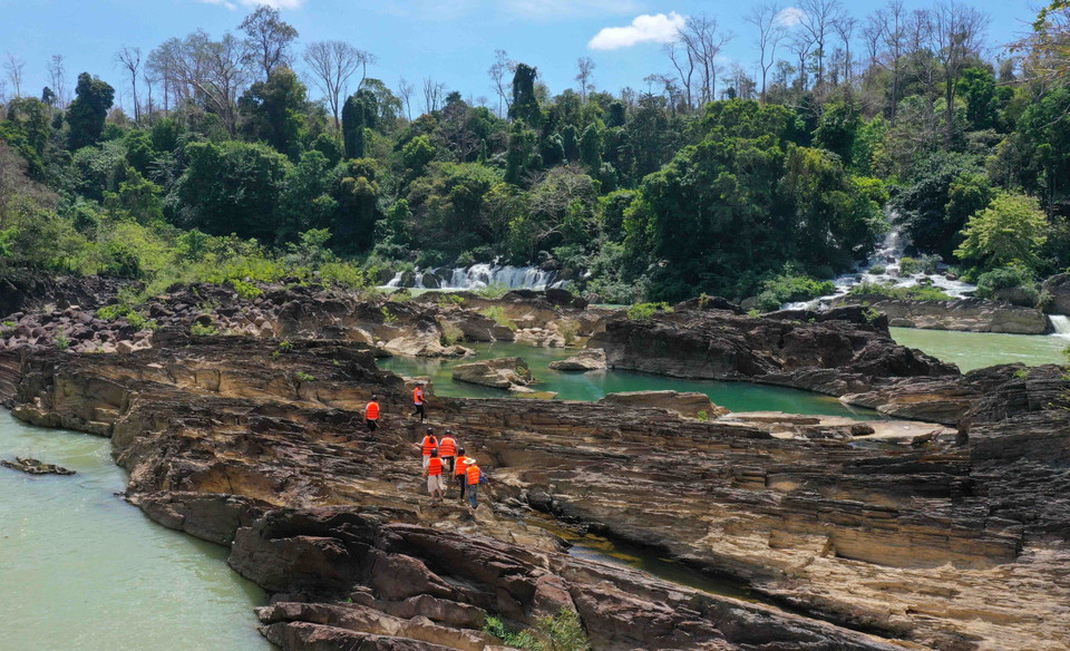 Du khách đi bộ trên những triền đá núi lửa cổ xưa ở cụm thác Gia Long-Dray Nur, tỉnh Đắk Lắk. (Ảnh: Hoài Thu/TTXVN)