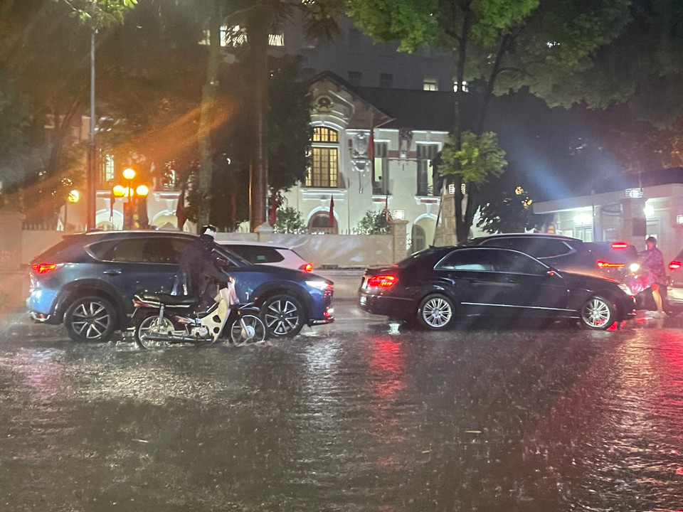 Ngập úng trên đoạn phố Nguyễn Du khiến các phương tiện khó di chuyển, một số người đi xe máy phải xuống dắt bộ. (Ảnh: Minh Hiếu/Vietnam+)