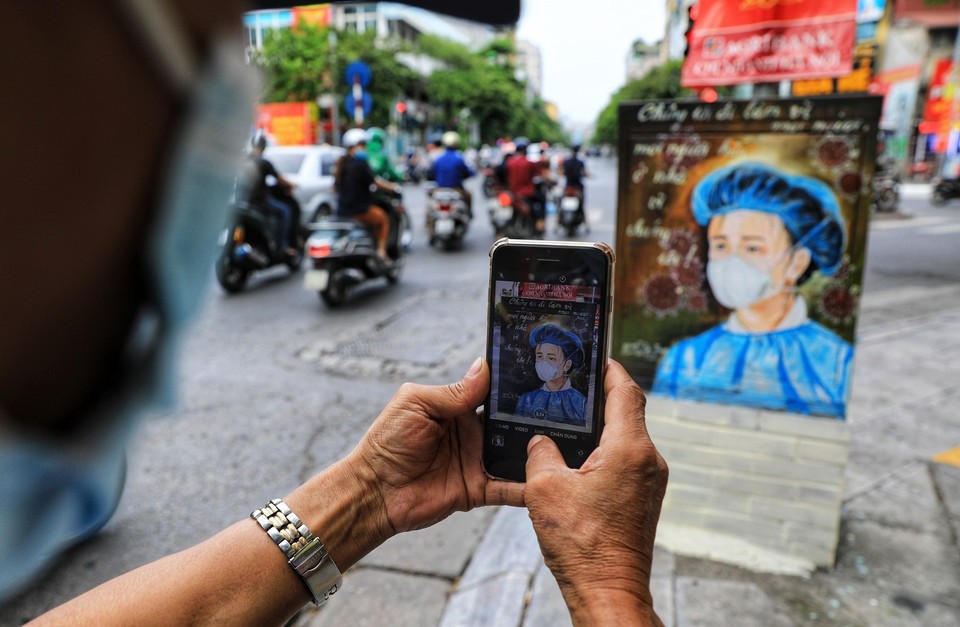 Người dân ấn tượng với những bức tranh cổ động trên bốt điện. (Ảnh: Thành Đạt/TTXVN)