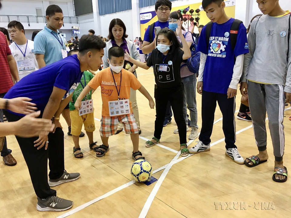 Các chuyên viên can thiệp hướng dẫn trẻ bị chứng Rối loạn phổ tự kỷ sinh sống trên địa bàn Thành phố Hồ Chí Minh chơi bóng đá. (Ảnh: Đinh Hằng/TTXVN)
