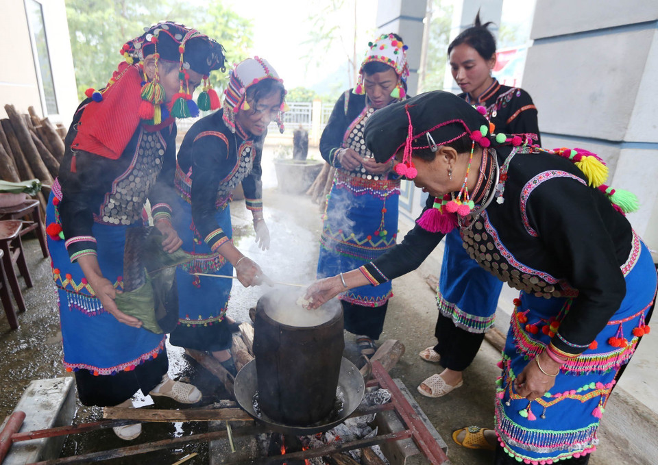 Các thành viên trong gia đình đồ xôi để giã bánh giầy. (Ảnh: Quý Trung/TTXVN)