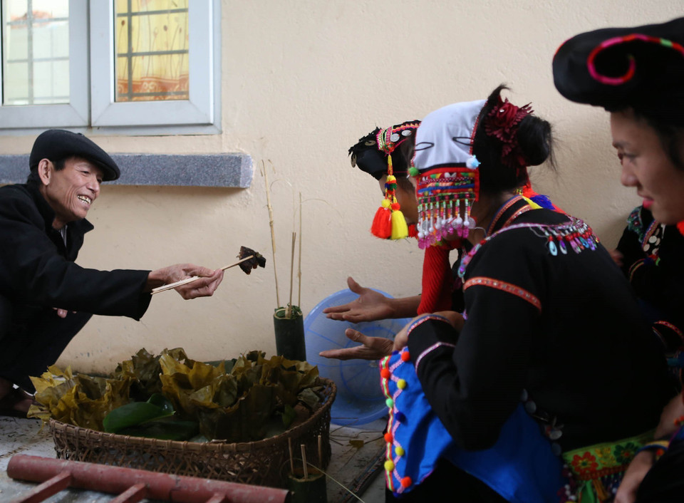 Sau khi cúng tổ tiên xong, thầy mo phát cho những thành viên mỗi người một miếng để ăn lấy may. (Ảnh: Quý Trung/TTXVN)