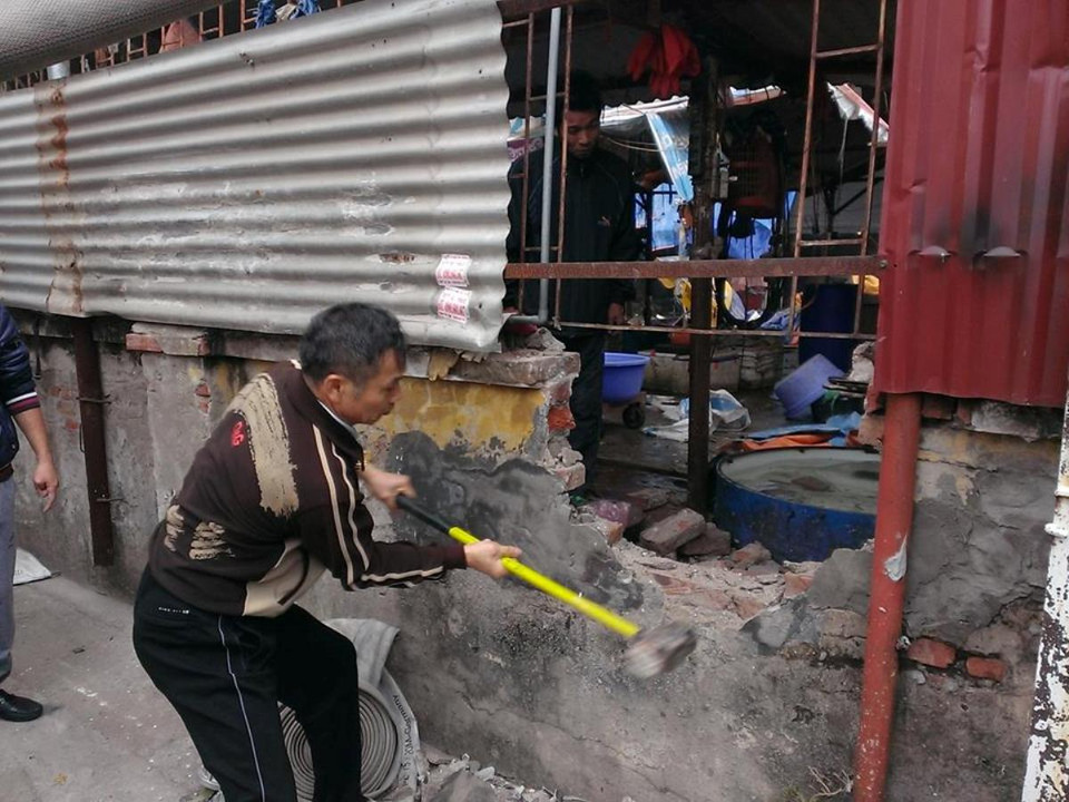 Người dân tiến hành đập tường để xử lý vụ cháy. (Ảnh: PV/Vietnam+)