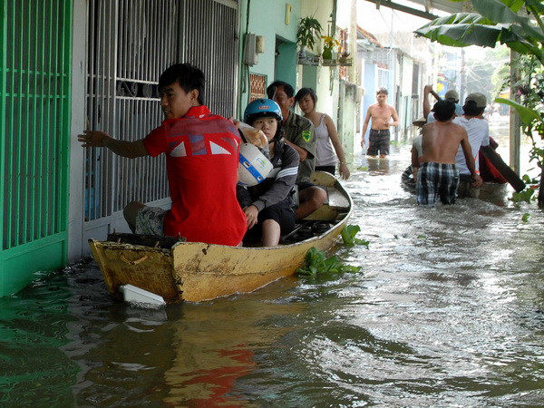 Người dân được sơ tán bằng thuyền đến các khu vực cao. (Ảnh: Mạnh Linh/TTXVN)