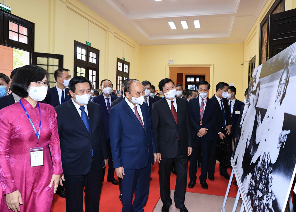 Phó Tổng Giám đốc Thông tấn xã Việt Nam Vũ Việt Trang giới thiệu trưng bày ảnh của TTXVN với Tổng Bí thư, Chủ tịch nước Lào Thongloun Sisoulith và Chủ tịch nước Nguyễn Xuân Phúc. (Ảnh: Thống Nhất/TTXVN)