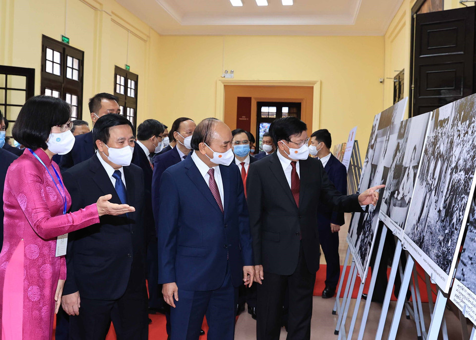 Phó Tổng Giám đốc Thông tấn xã Việt Nam Vũ Việt Trang giới thiệu trưng bày ảnh của TTXVN với Tổng Bí thư, Chủ tịch nước Lào Thongloun Sisoulith và Chủ tịch nước Nguyễn Xuân Phúc. (Ảnh: Thống Nhất/TTXVN)